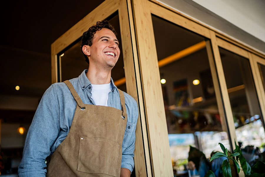 Male business owner in smock standing in entrance to his store