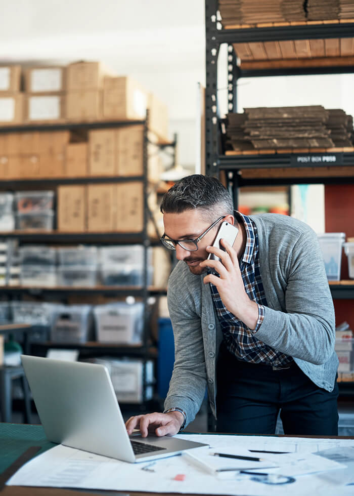 Man on phone and computer in warehouse