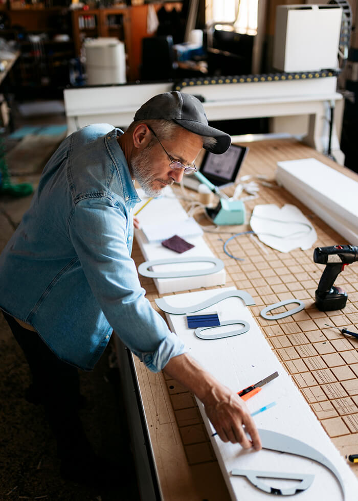 Senior craftsman working on signage project in workshop