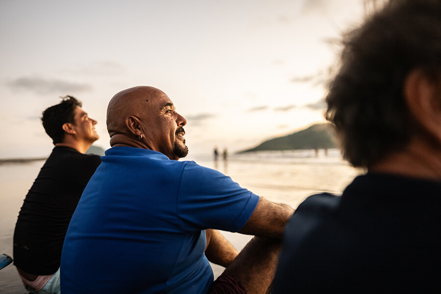 Three men sitting by the water