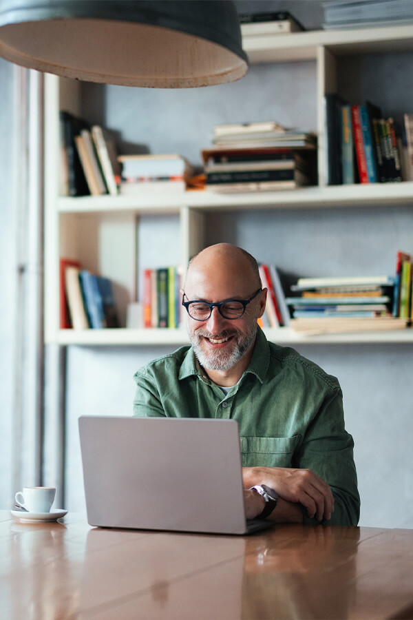Man sitting in front of bookshelf with laptop