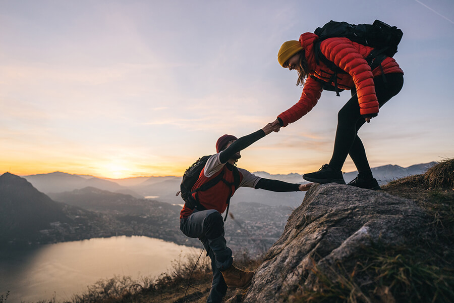 Person helping other hiker at top of summit