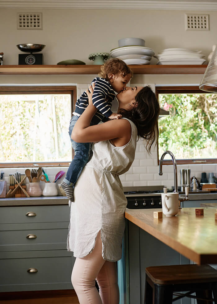 Woman kissing child in kitchen of new home
