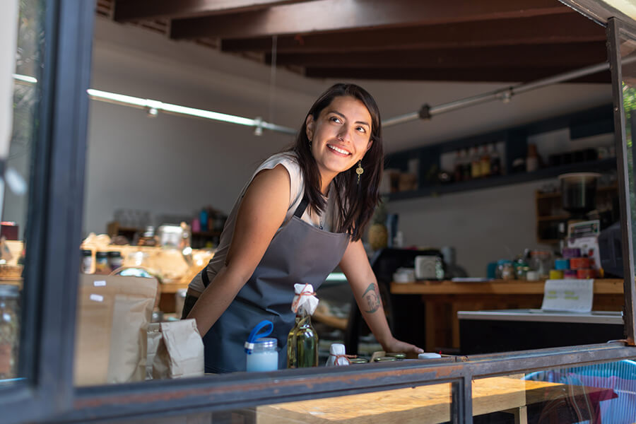 Woman looking out window from behind counter at her shop