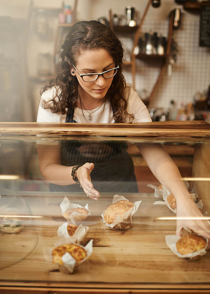 Woman putting out pastries at bakery